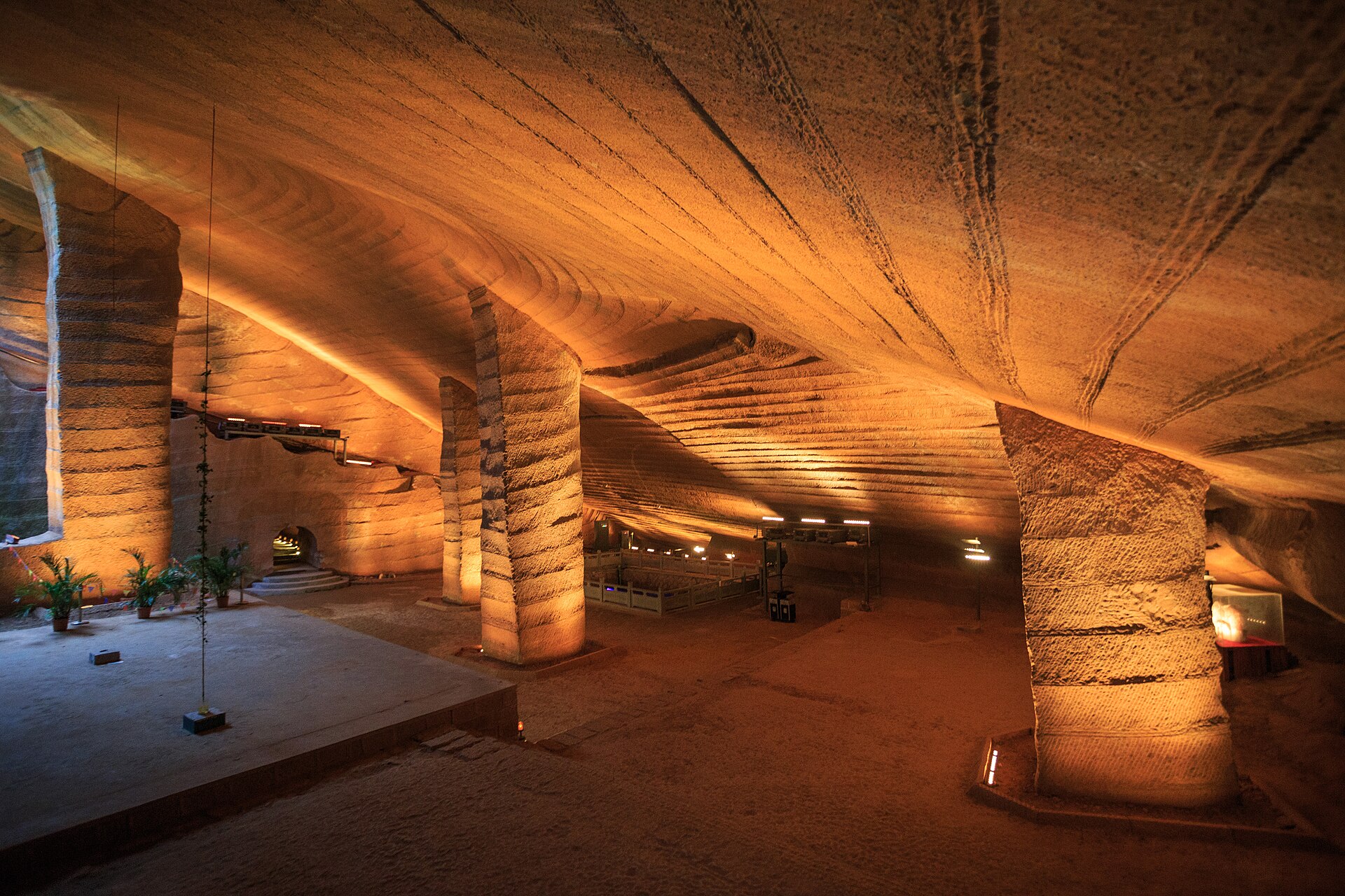 A wide-angle photo inside one of the Longyou Caves, showing a vaulted stone ceiling and two tapered stone pillars, all covered edge to edge in uniform parallel chisel-mark ridges.